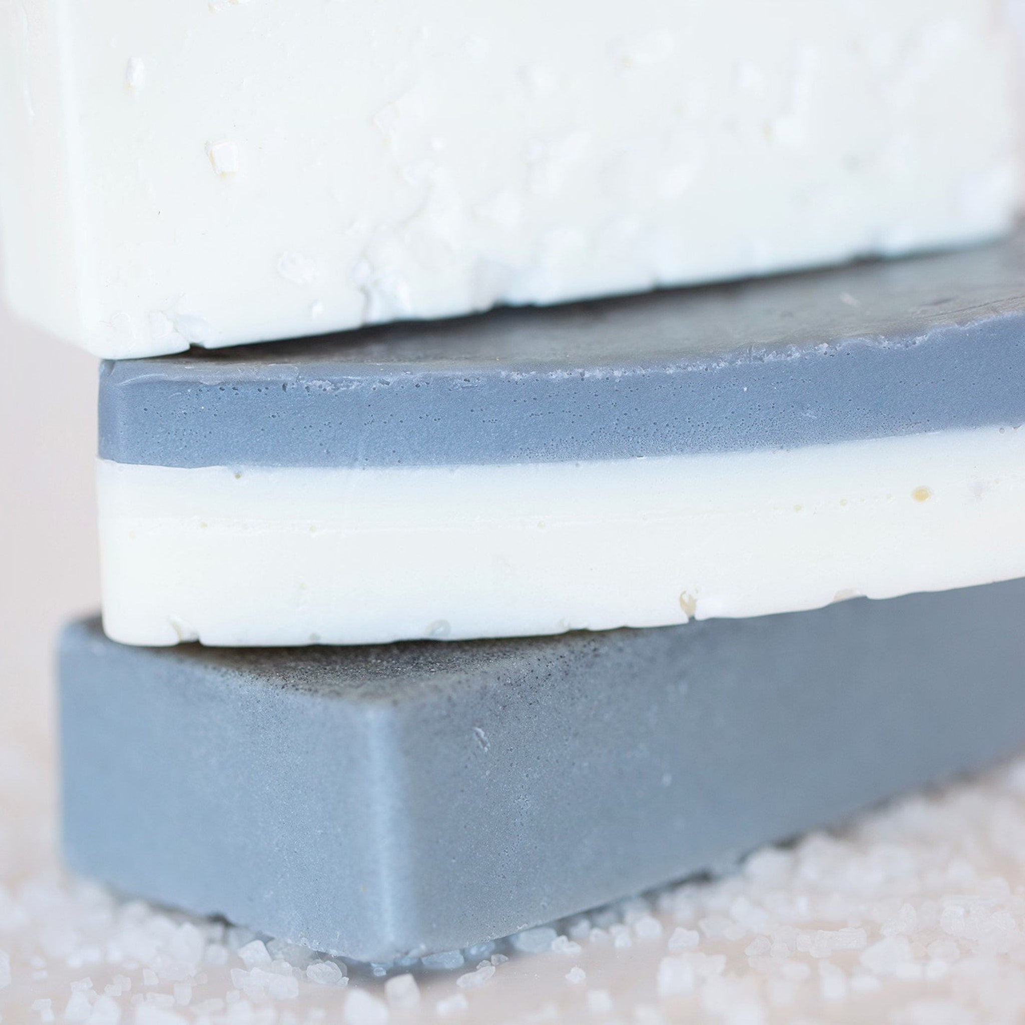 Soap bars in white, gray, and layered design, stacked with salt crystals around