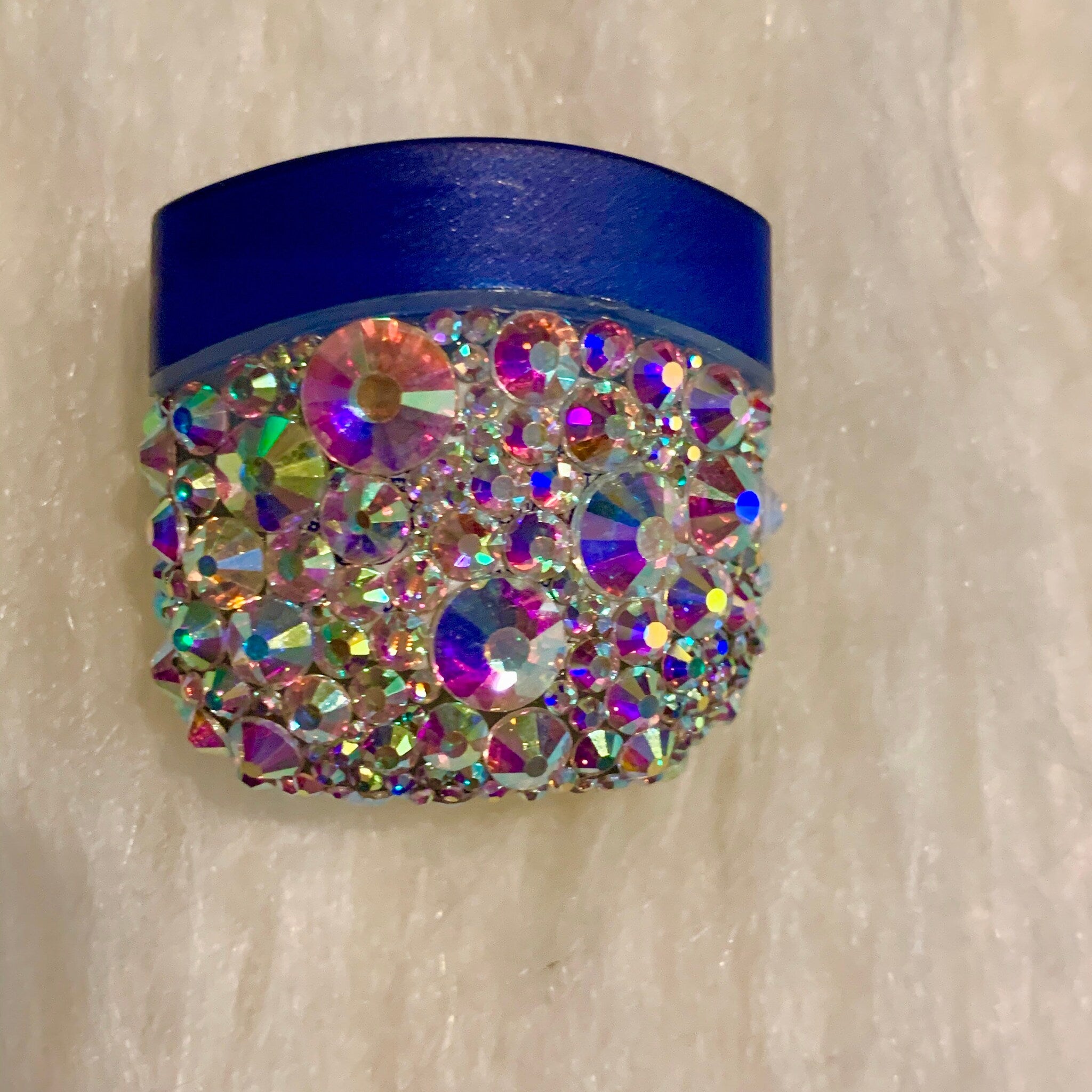 Blue and iridescent rhinestone container with jeweled embellishments on white background