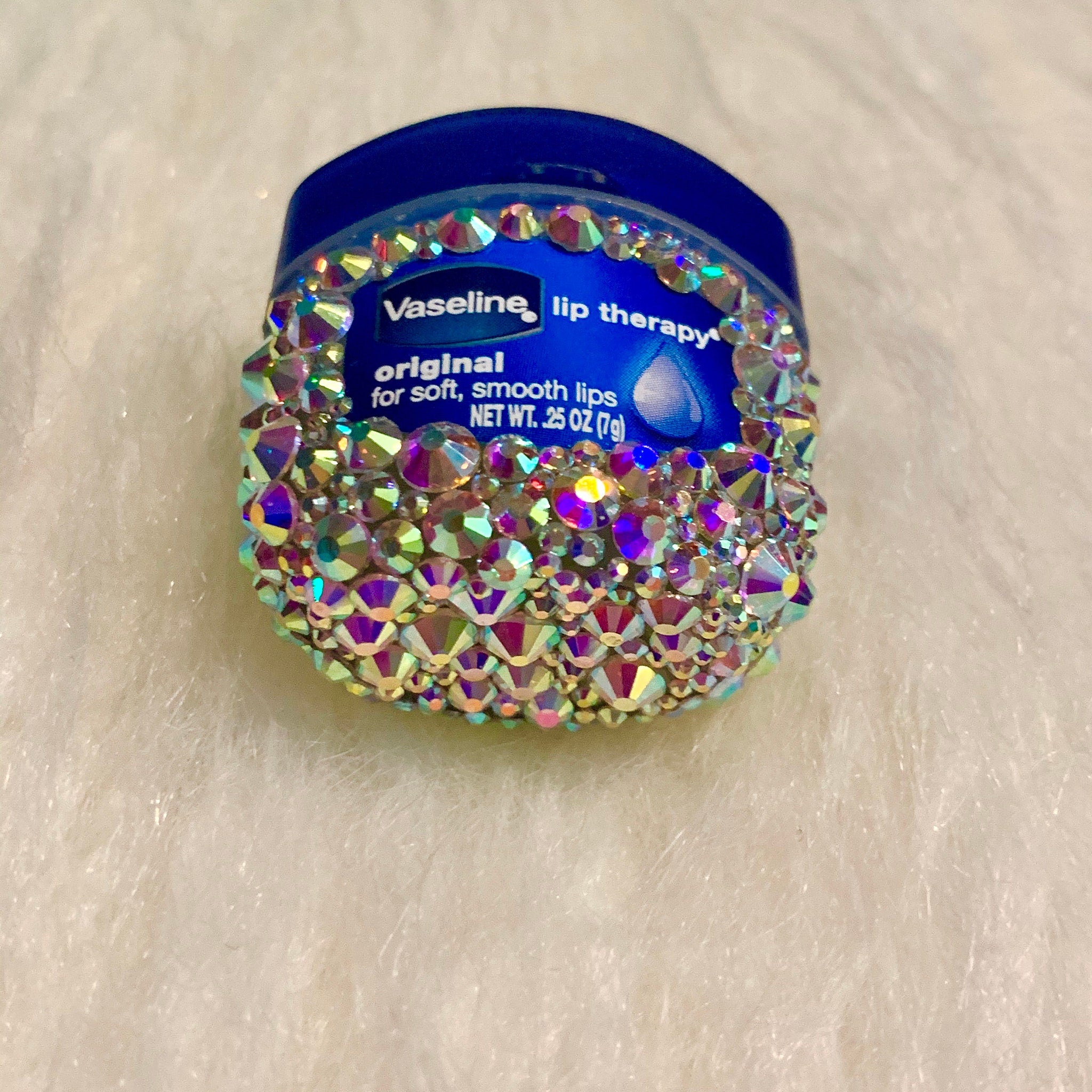 Lip therapy container with blue lid, covered in iridescent rhinestones, Vaseline branding visible