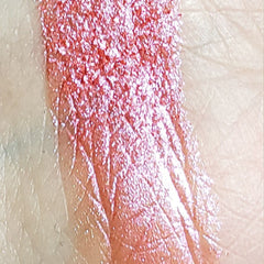 Close-up of fingertips applying shimmery bronze eyeshadow from a compact palette