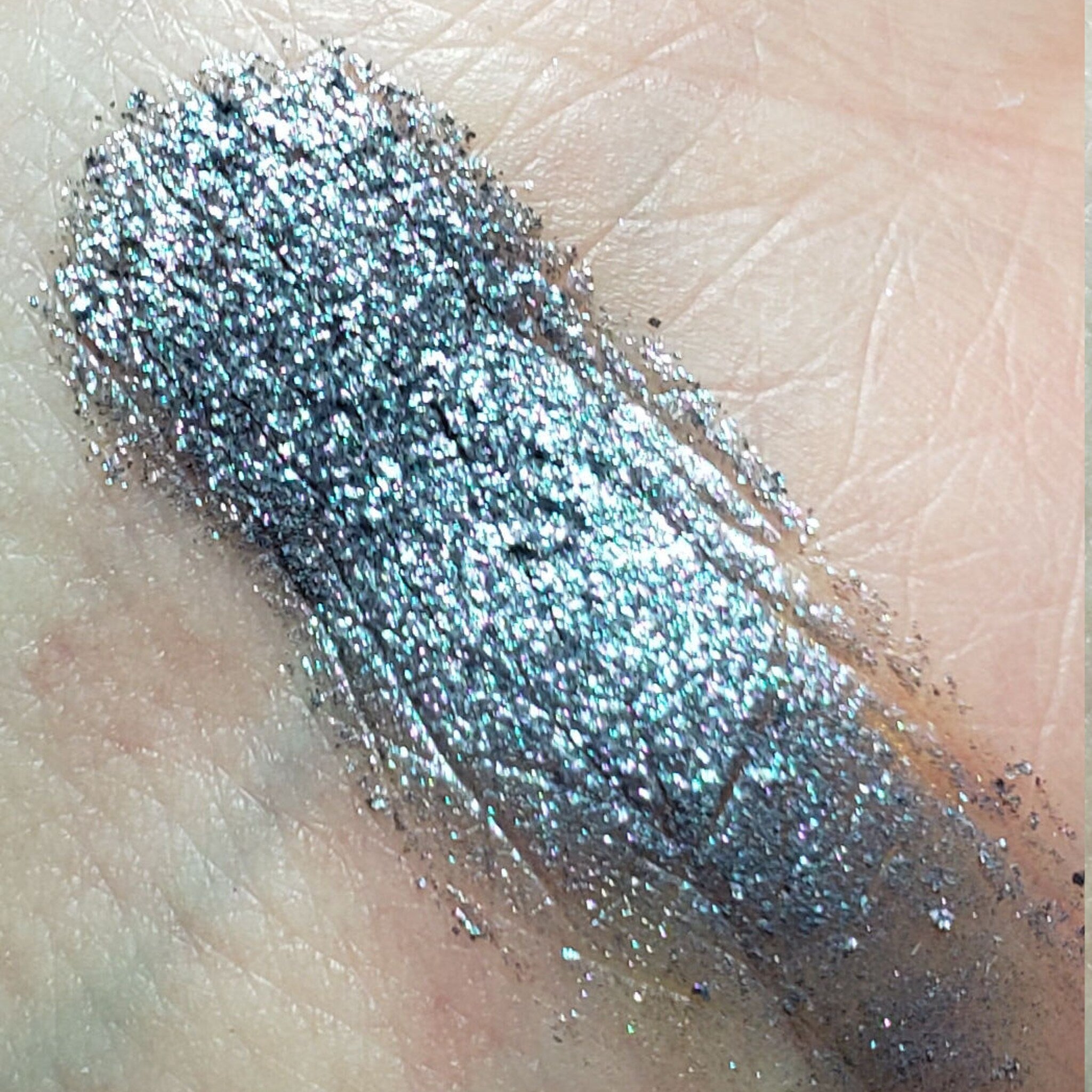 Close-up of shimmering eyeshadow palette showing four vibrant shades with metallic finish in compact case