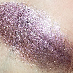 Close-up of four shimmering eyeshadow pans in bronze, gold, rose, and plum with metallic finish