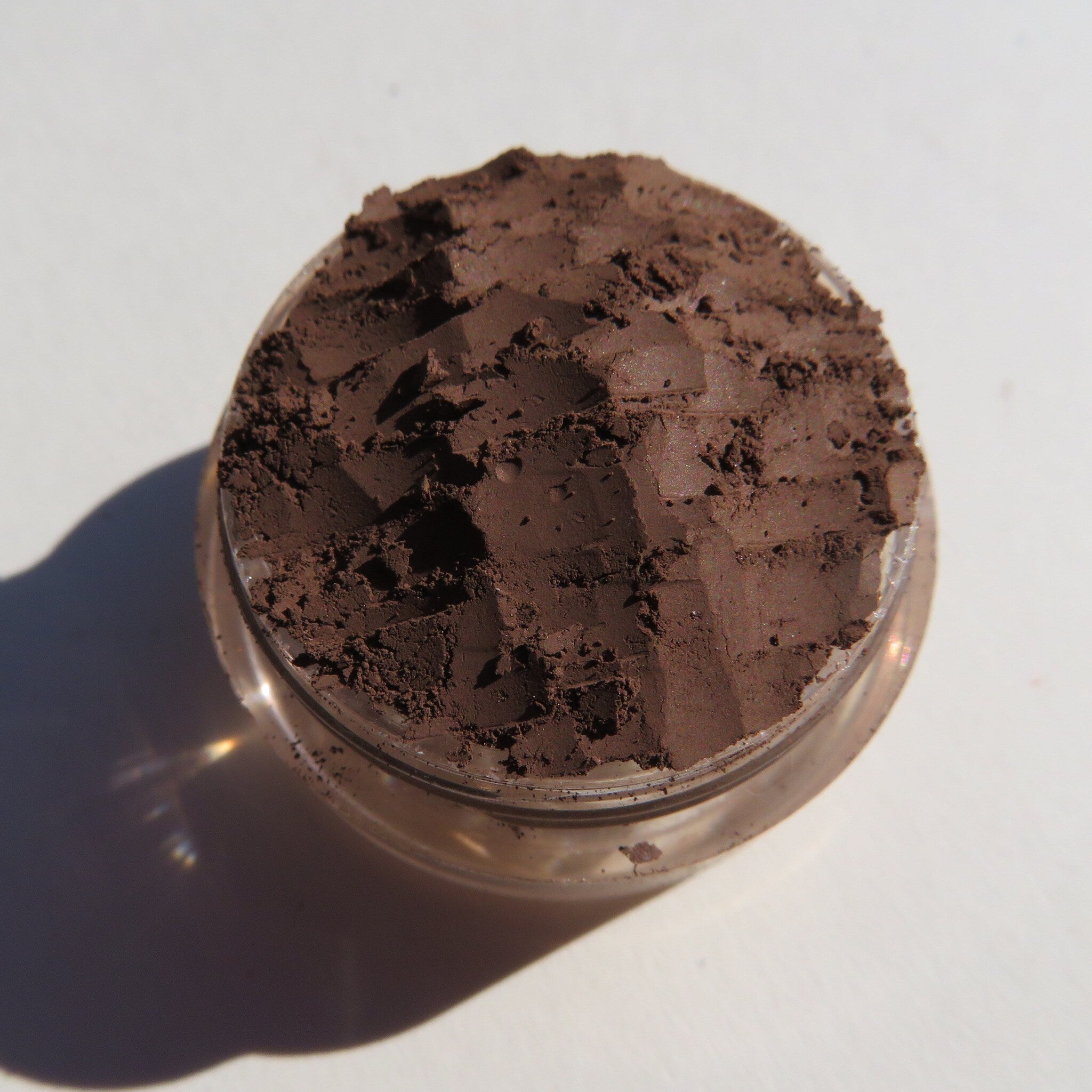 Dark matte brown mineral eye shadow in round black compact with clear lid and Zookeeper logo