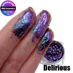 Close-up of Delirious Chromaflake eye shadow flakes showcasing multichrome metallic shift from purple to green