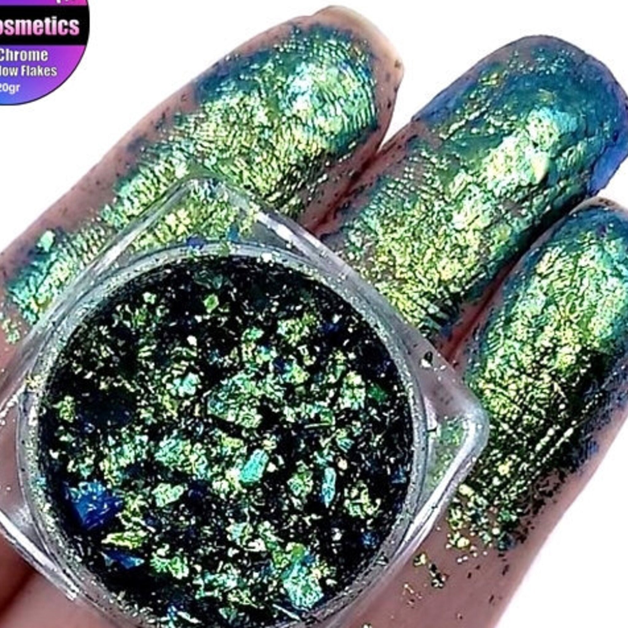 Multichrome eyeshadow flakes in shifting iridescent hues inside a sleek black compact with gold accents