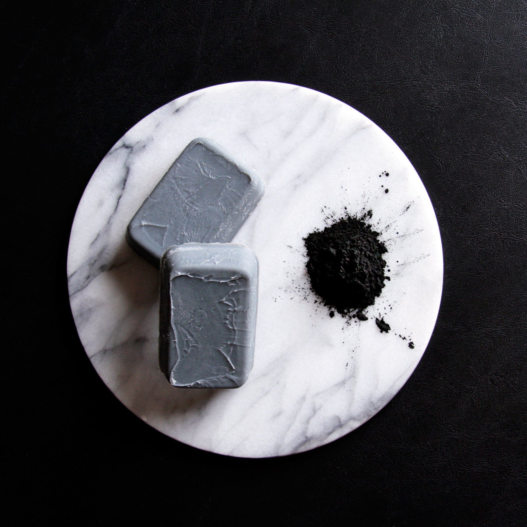 Gray soap bars on white marble, with black powder and black background