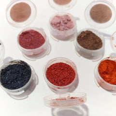 Eye makeup eyeshadow in various colors, clear plastic containers, powder texture, displayed on white surface