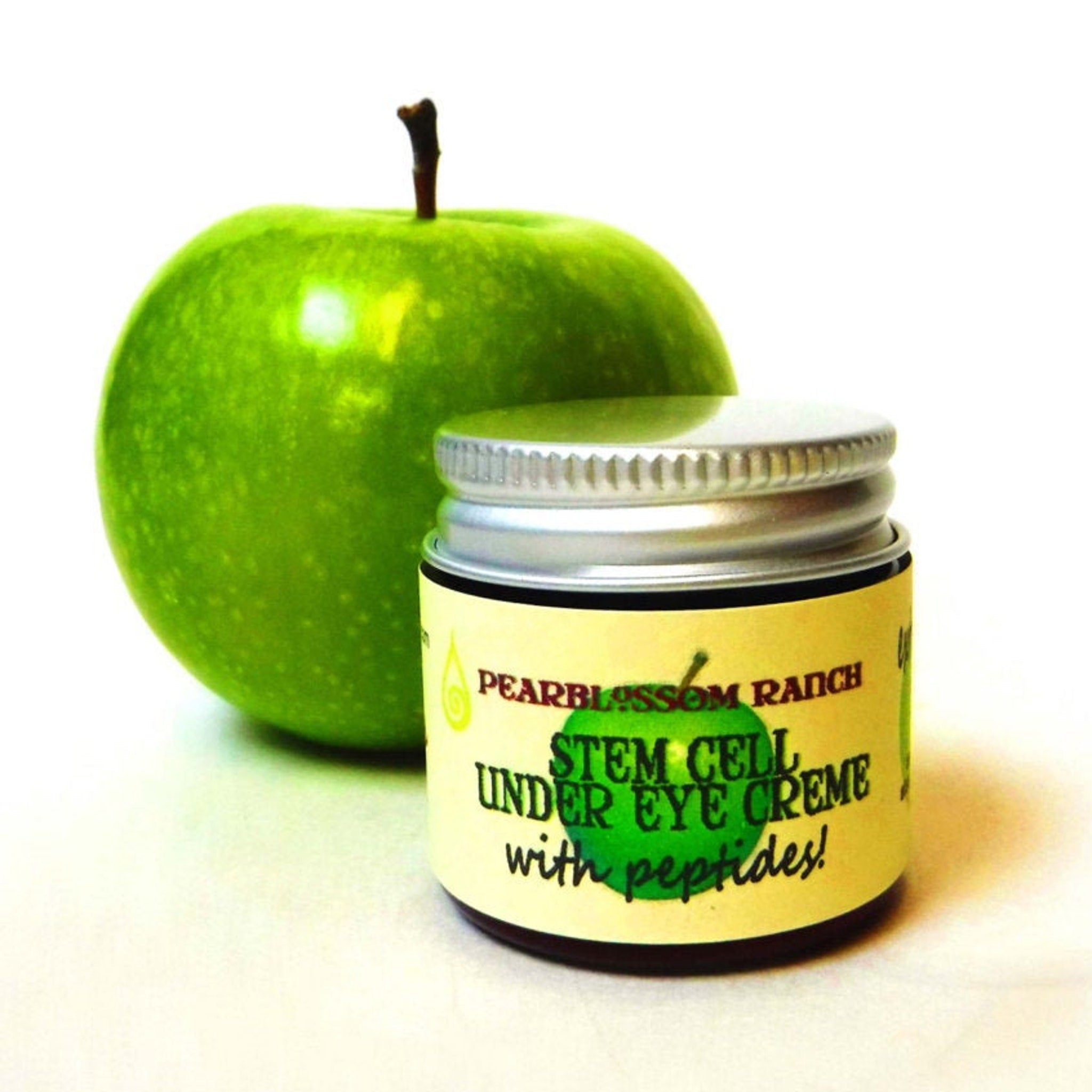 Stem cell eye creme jar with silver lid and green apple, Pearblossom Ranch branding visible