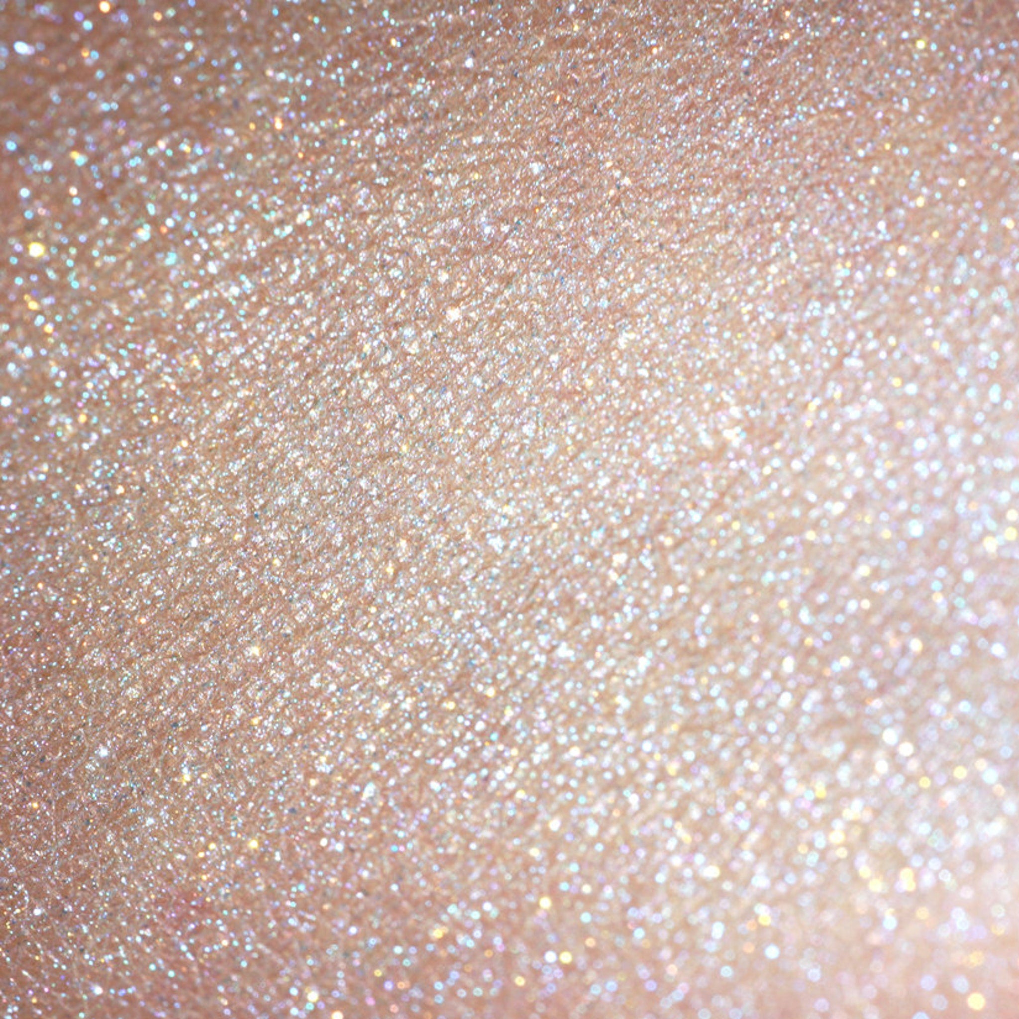 Swatch of iridescent turquoise and orange vegan eyeshadow with shimmer finish on fingertip