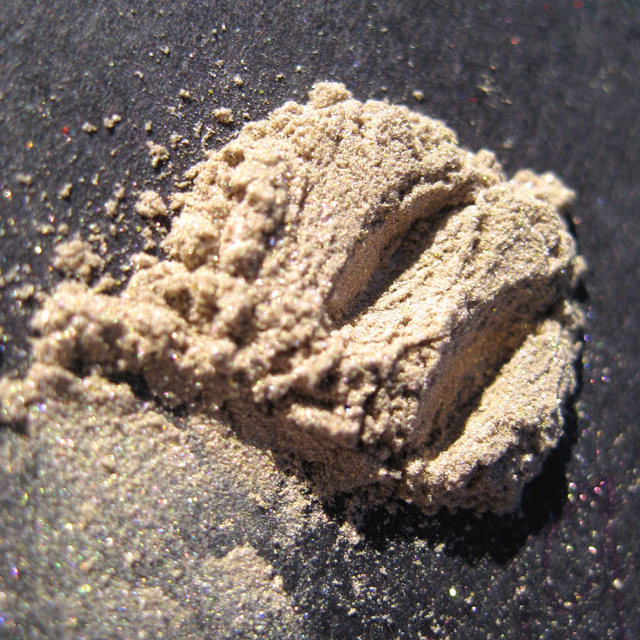 Open compact showing loose mineral eyeshadow in sheer tan with gold and green shimmer, vegan silk finish