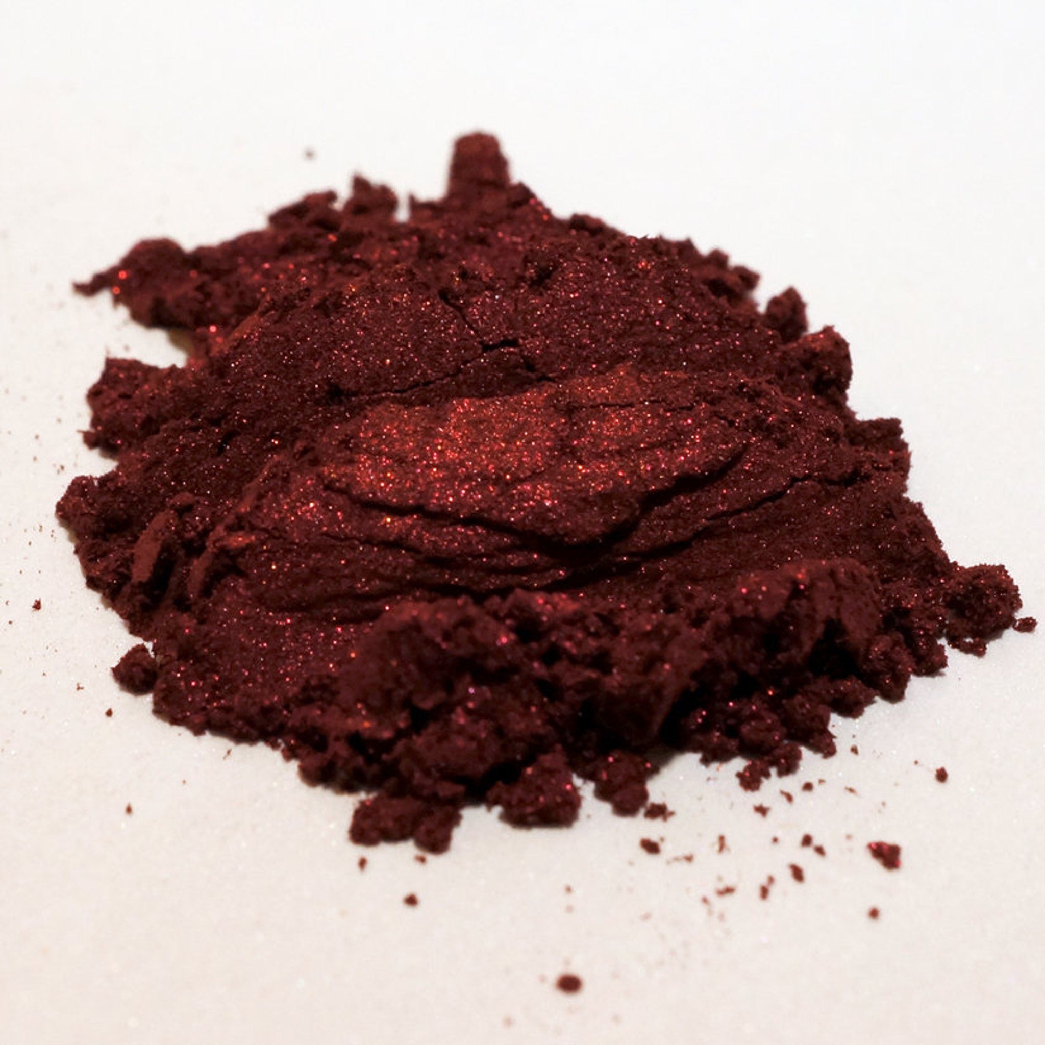 Close-up of blood red metallic loose mineral eyeshadow with intense shimmer particles scattered across surface
