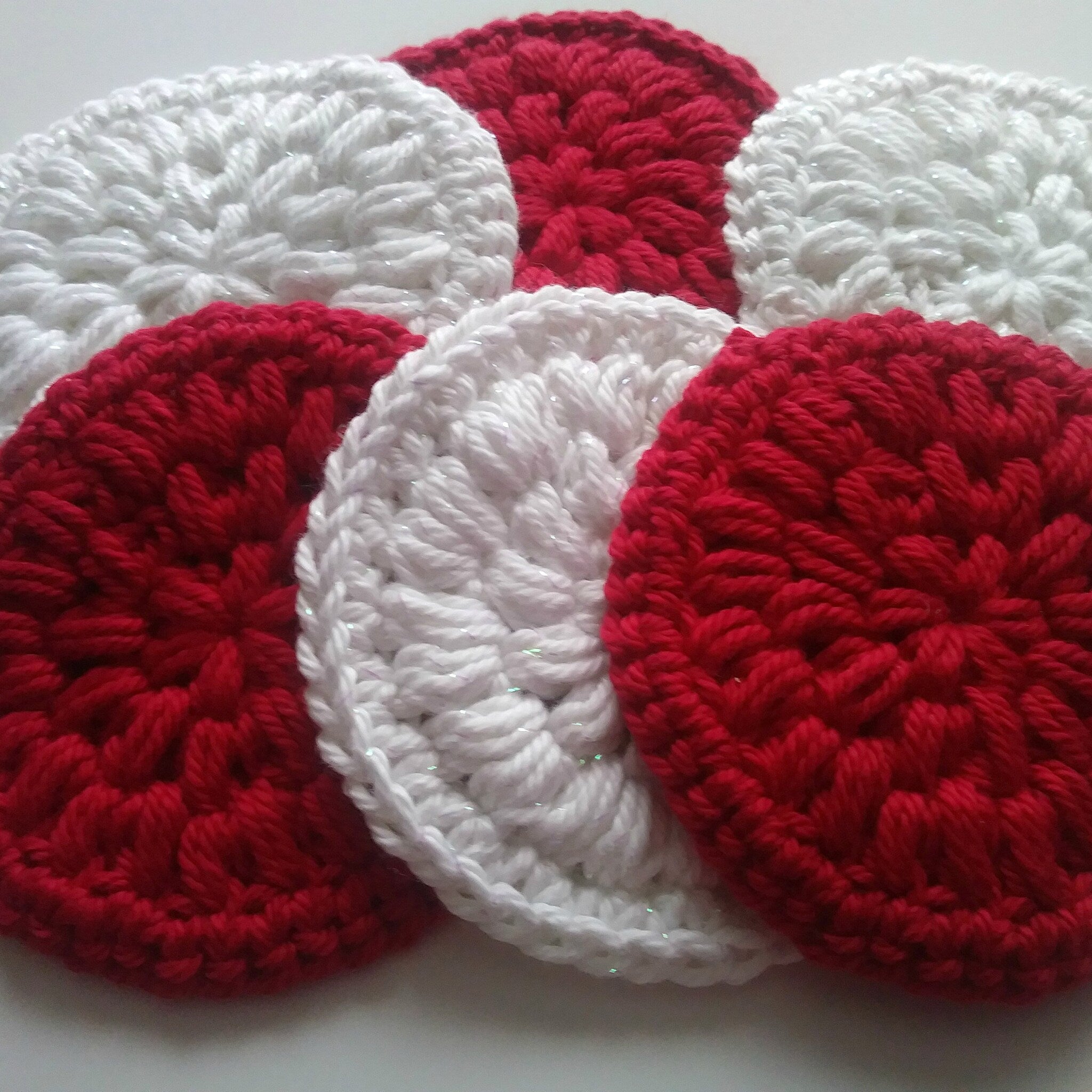 Crocheted coasters in red and white yarn with textured stitch pattern