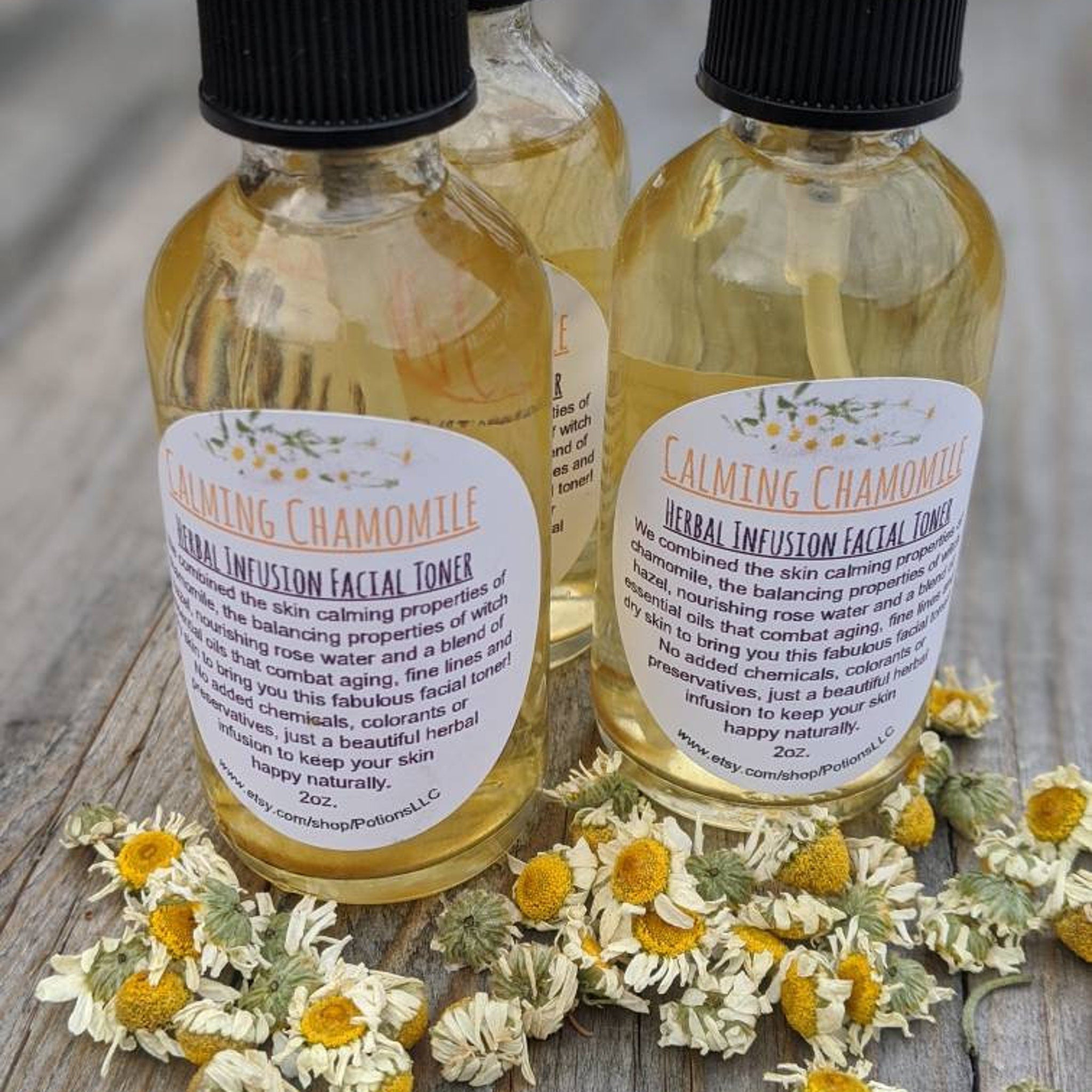 Herbal facial toner bottles with black caps, clear liquid, and white labels on wood surface with dried flowers