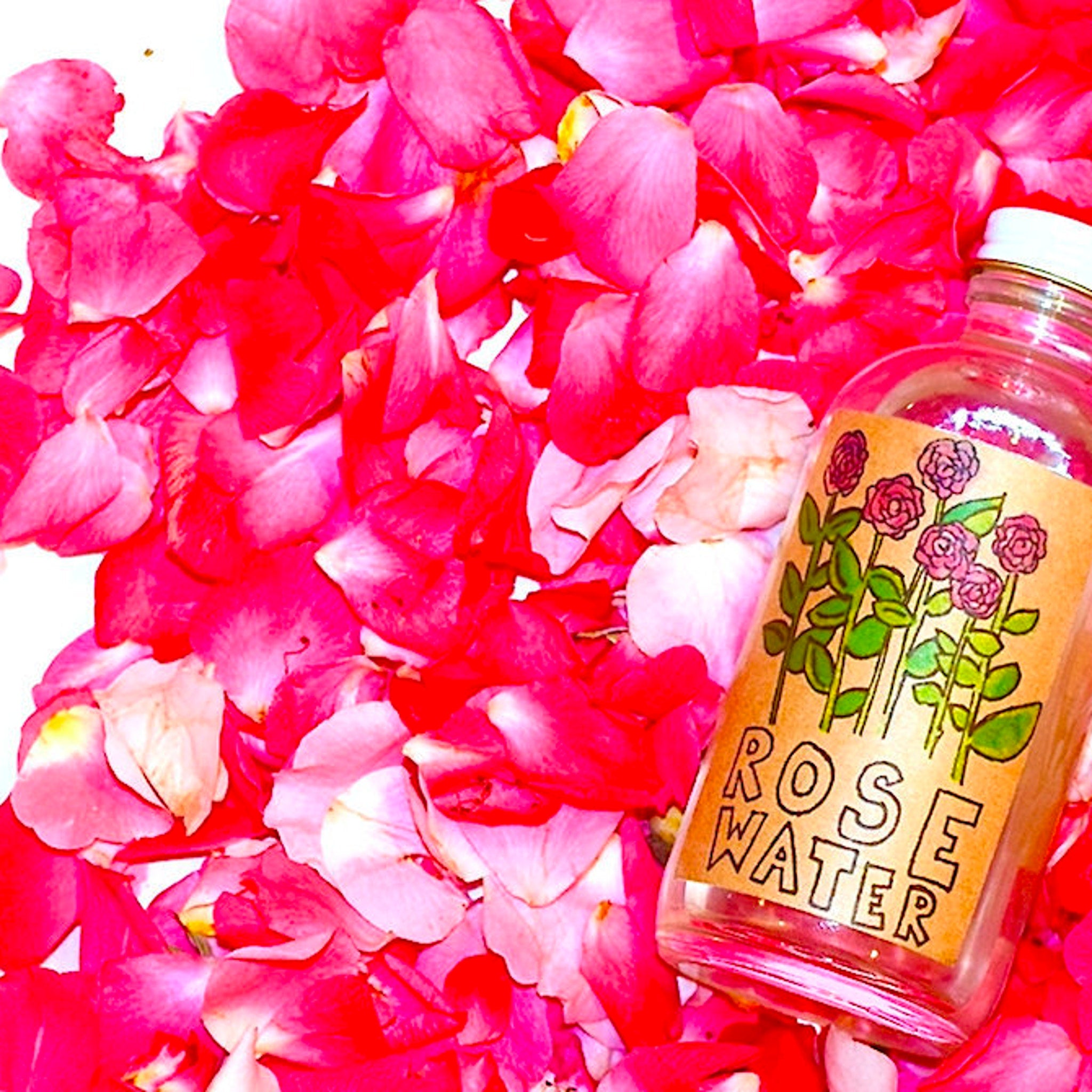 Rose water bottle with red rose petals, clear glass, and ROSE WATER label