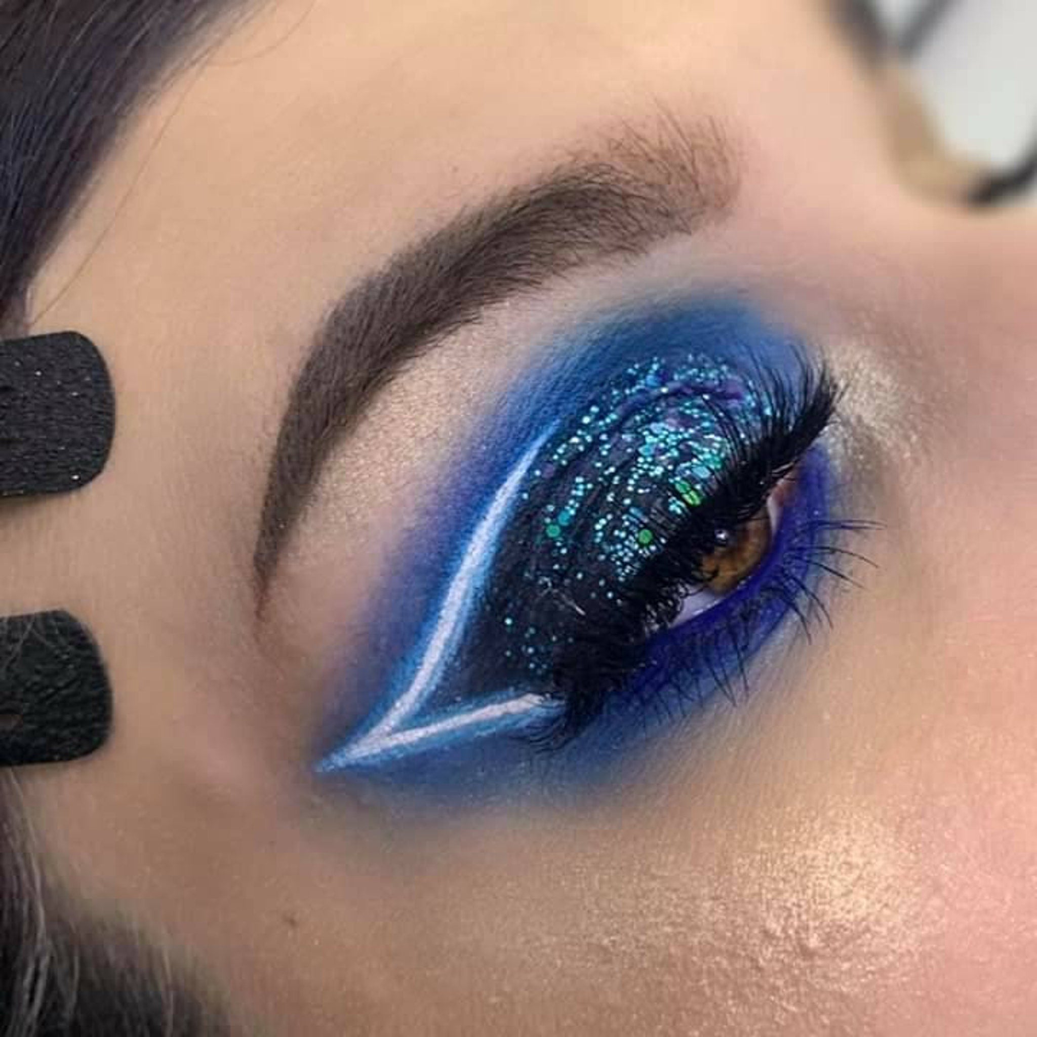 Open compact showing mermaid scales eye shadow palette with iridescent teal and purple hues