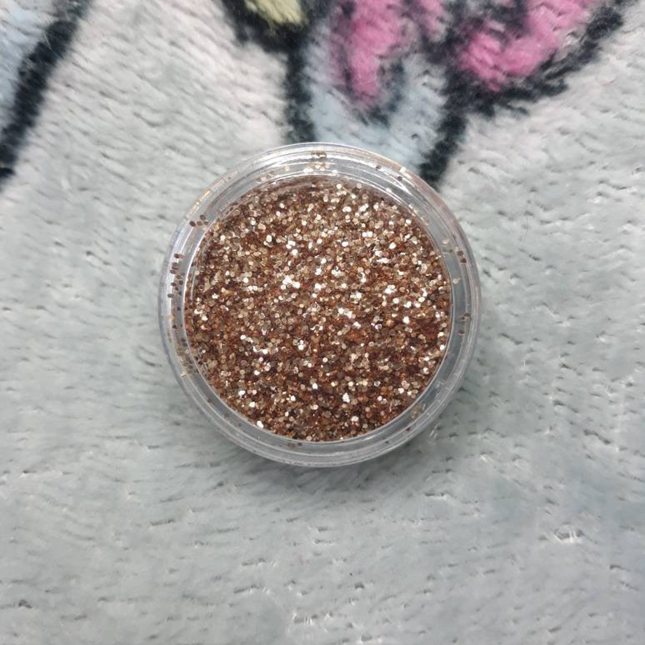 Deception Eye Shadow compact with mirrored lid and embossed logo, showcasing deep plum shade in square pan.