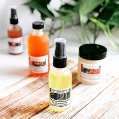 Cleansing oil bottles in yellow and orange, black pump tops, on a wood surface, Leaf Seed Berry brand label