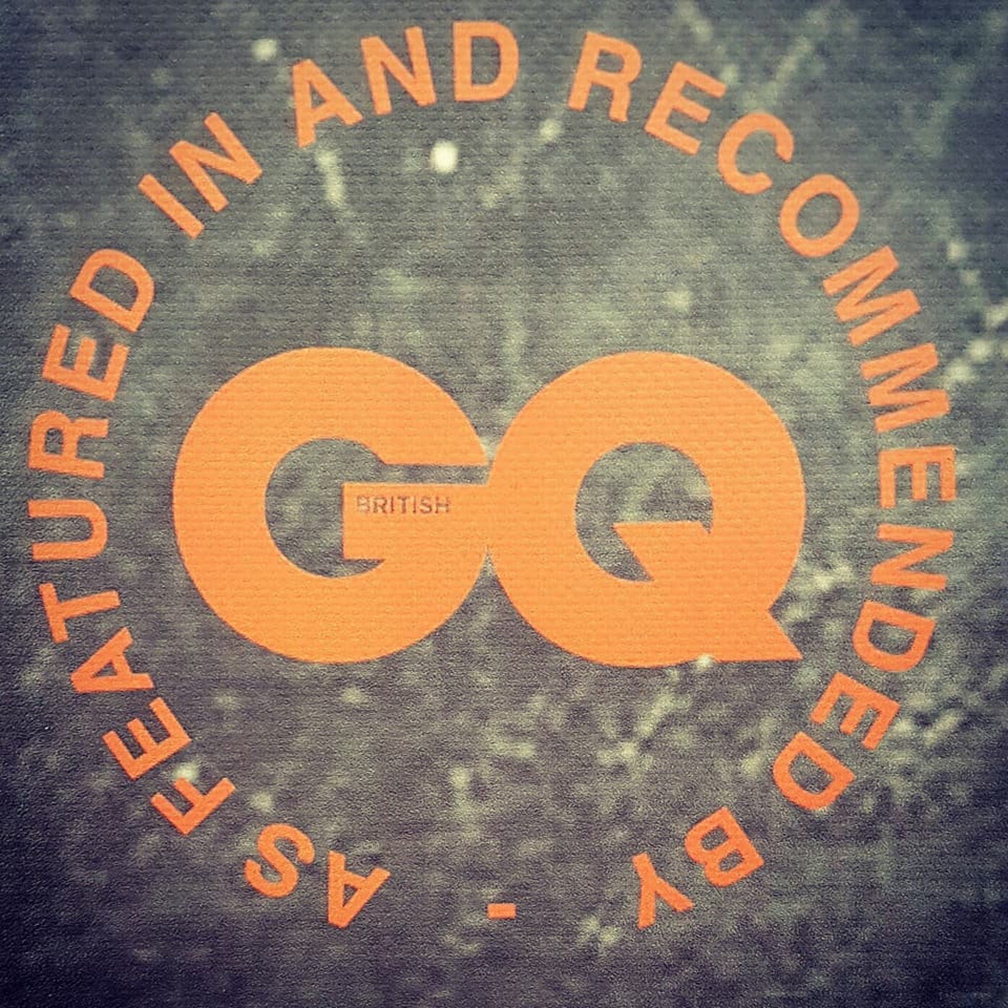 GQ logo in orange with text on dark textured background, featured and recommended by GQ British