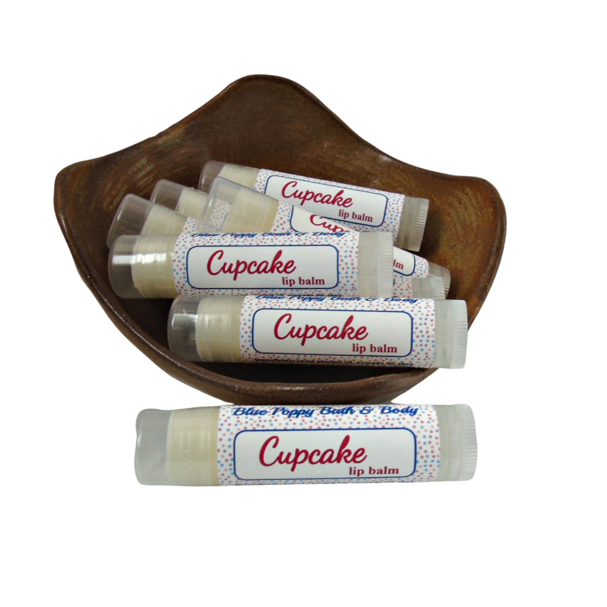 Lip balm tubes with "Cupcake" label, white and patterned, in a brown bowl.