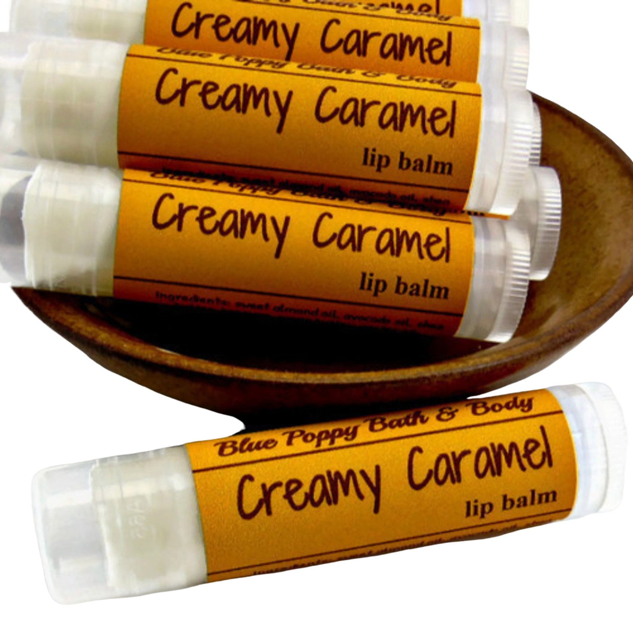 Lip balm tubes with yellow labels, clear plastic, and "Creamy Caramel" text in a wooden bowl.
