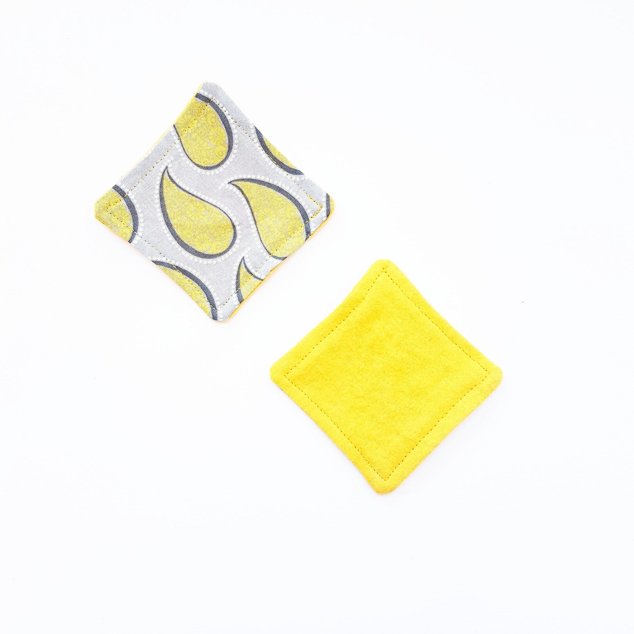 Yellow and gray patterned fabric squares with yellow stitching and a solid yellow square
