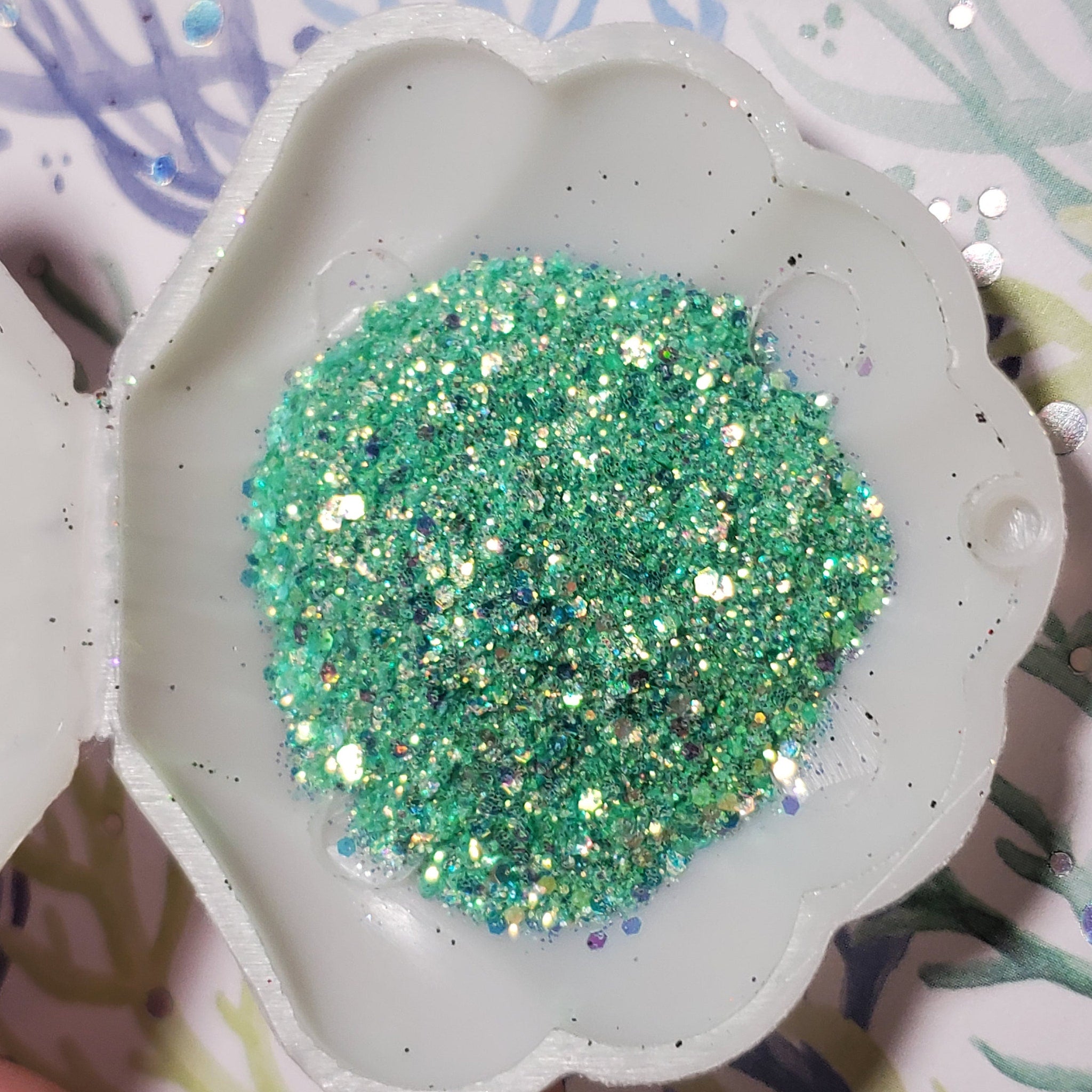Side view of iridescent mermaid glitter gel eyeshadow pot showing multi-color shimmer reflections