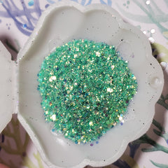 Side view of iridescent mermaid glitter gel eyeshadow pot showing multi-color shimmer reflections