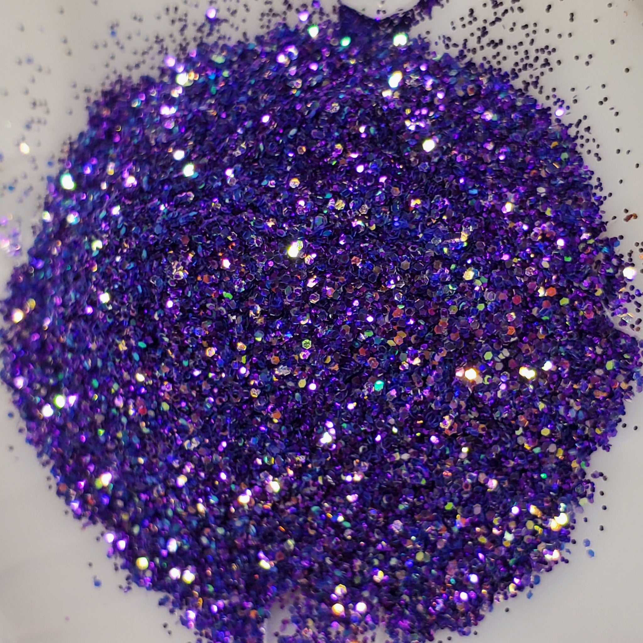 Side view of vibrant purple glitter eye shadow gel pot with metallic lid catching light