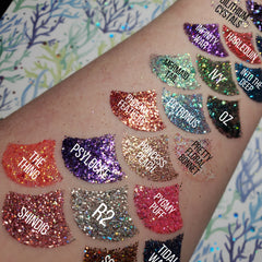 Close-up of fingers applying shimmering violet glitter eye shadow gel to eyelid