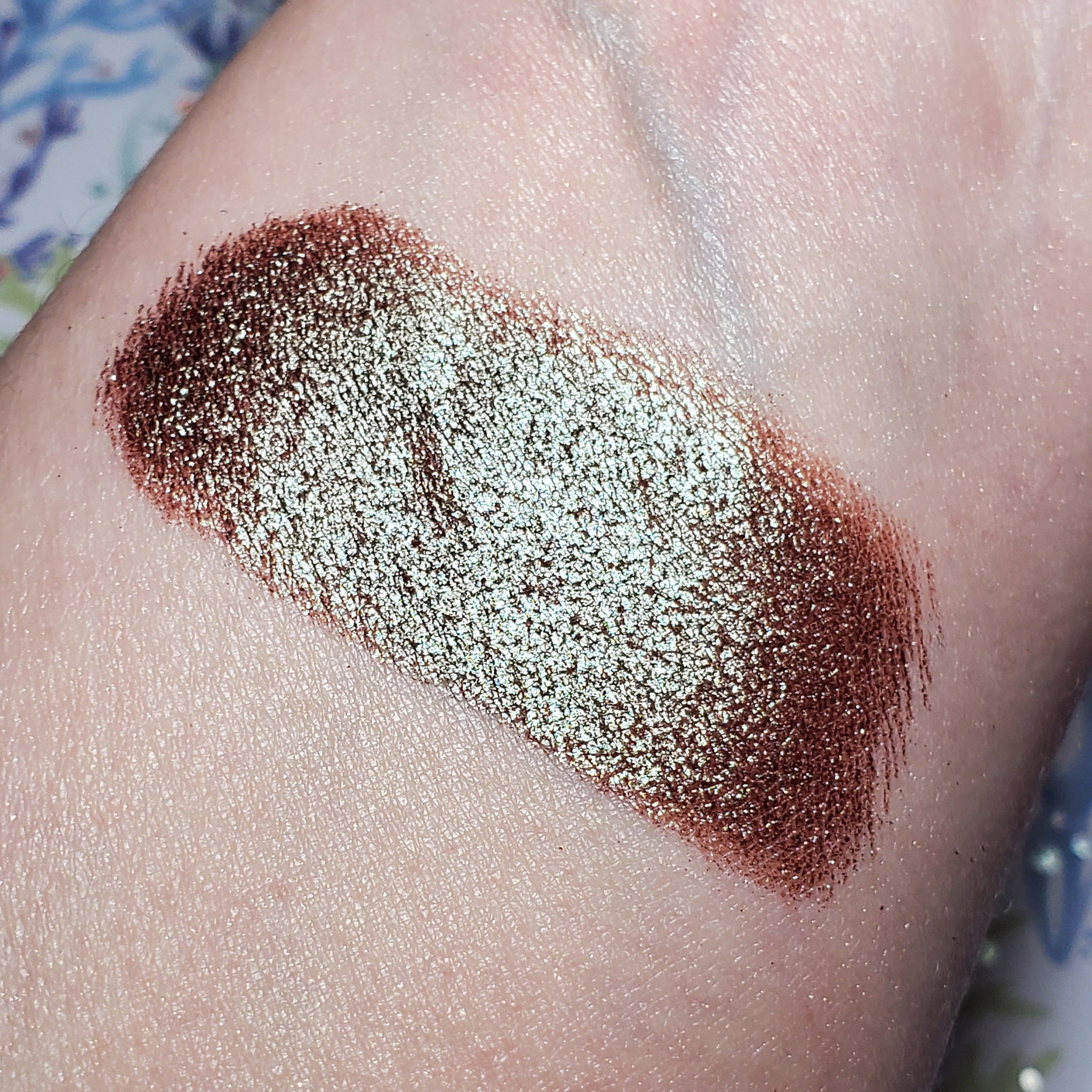 Close-up of a hand applying shimmering taupe eye shadow with a fluffy blending brush