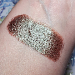 Close-up of a hand applying shimmering taupe eye shadow with a fluffy blending brush