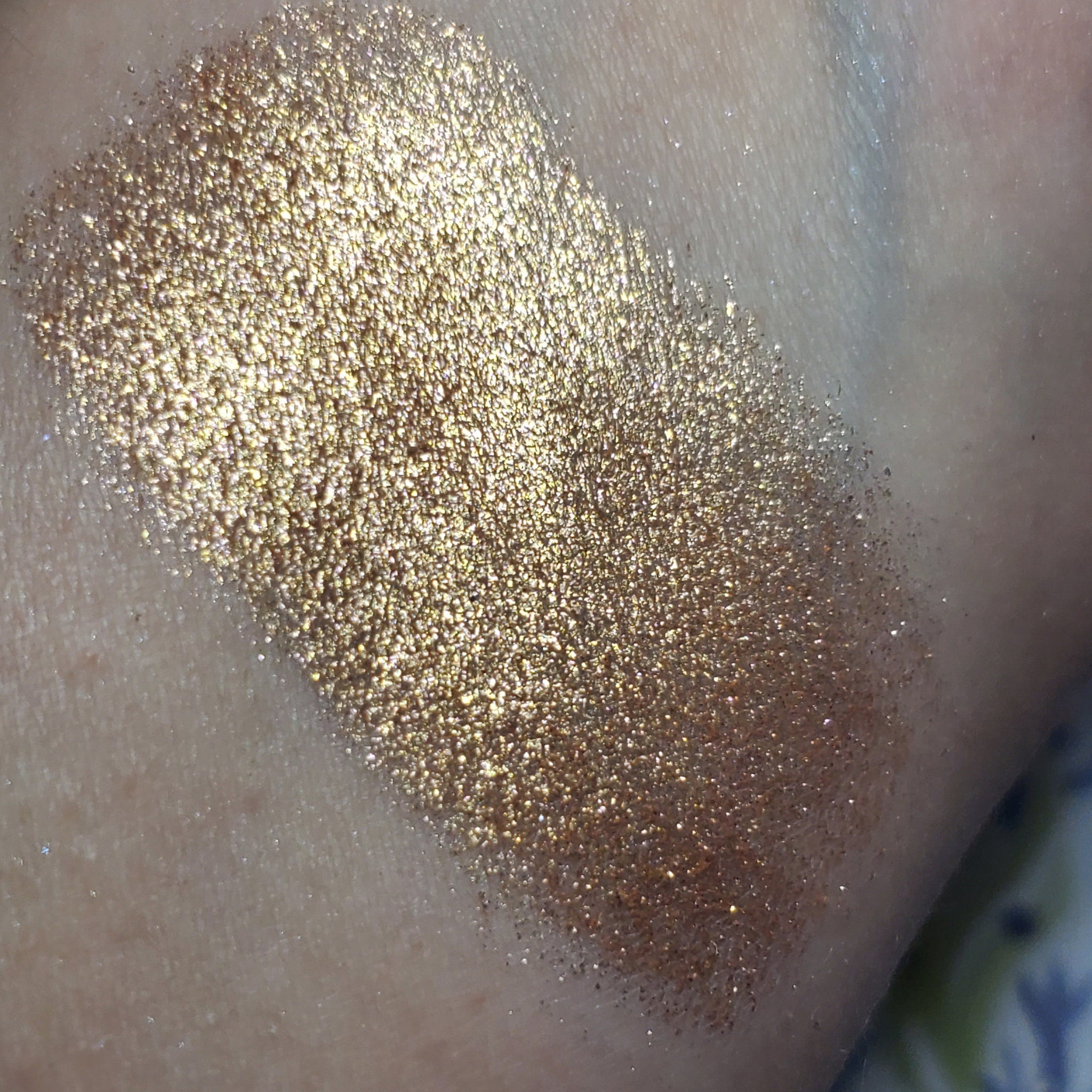 Close-up of a makeup brush applying shimmering bronze Dobby Eye Shadow to eyelid crease