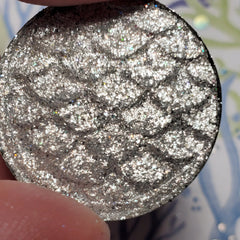 Close-up of shimmering bronze and taupe eye shadow pans with smooth satin finish in sleek black palette
