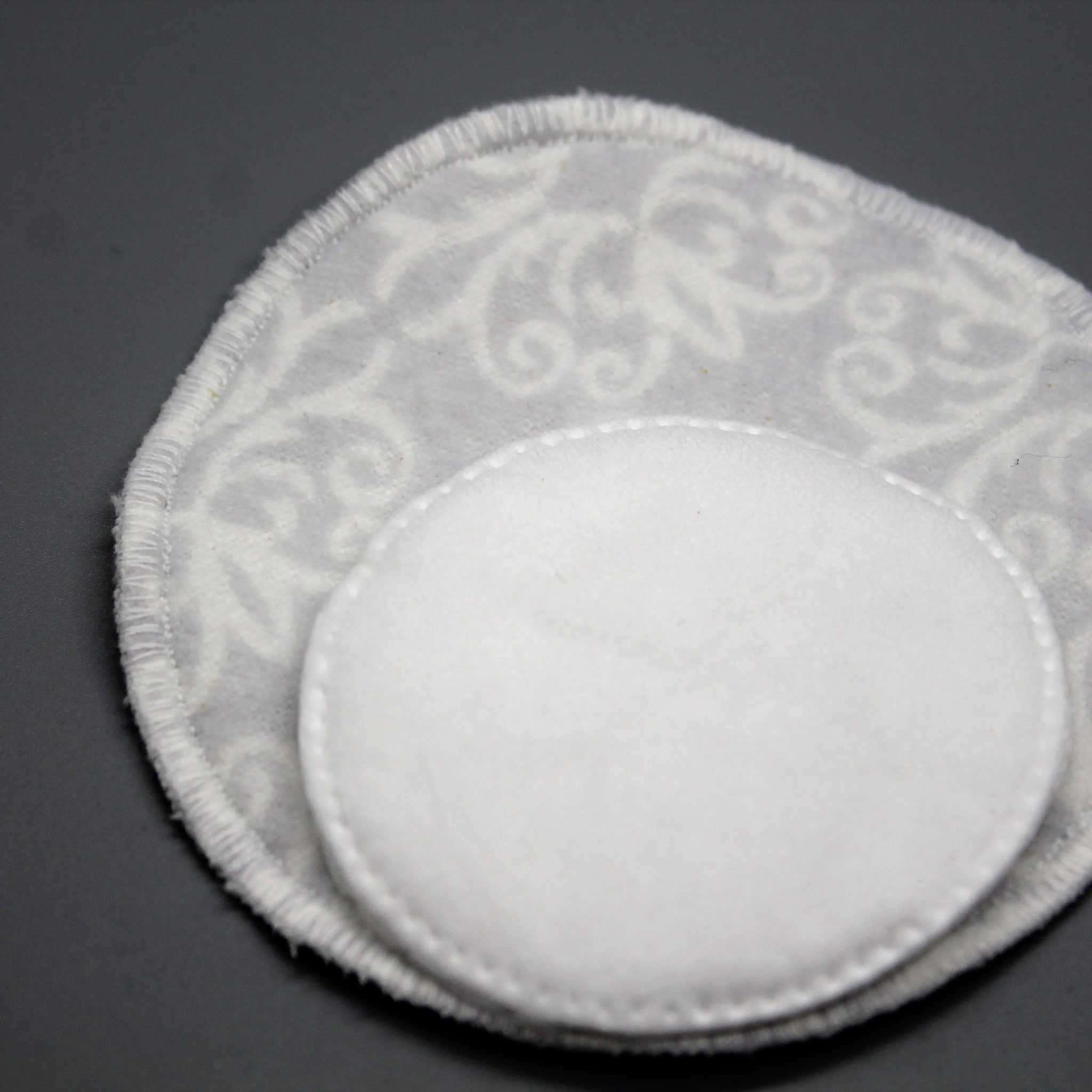 White round cotton pads with floral pattern and stitched edges