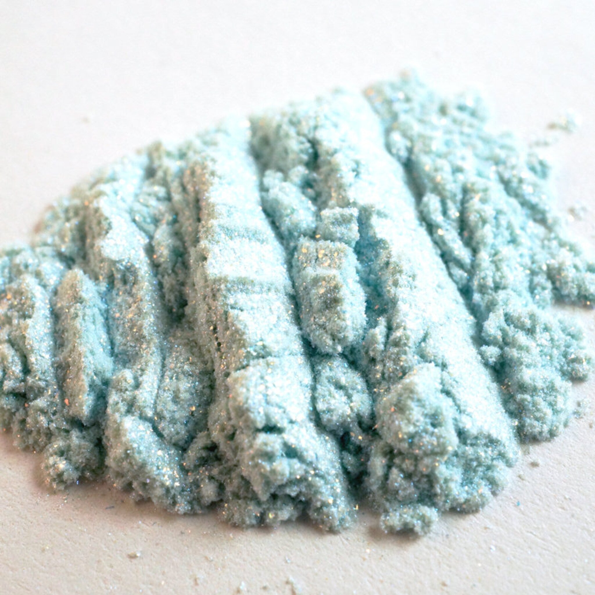 Side view of La Sirena Aqua Eye Shadow duo showing turquoise and orange iridescent shimmer pans at 45-degree angle