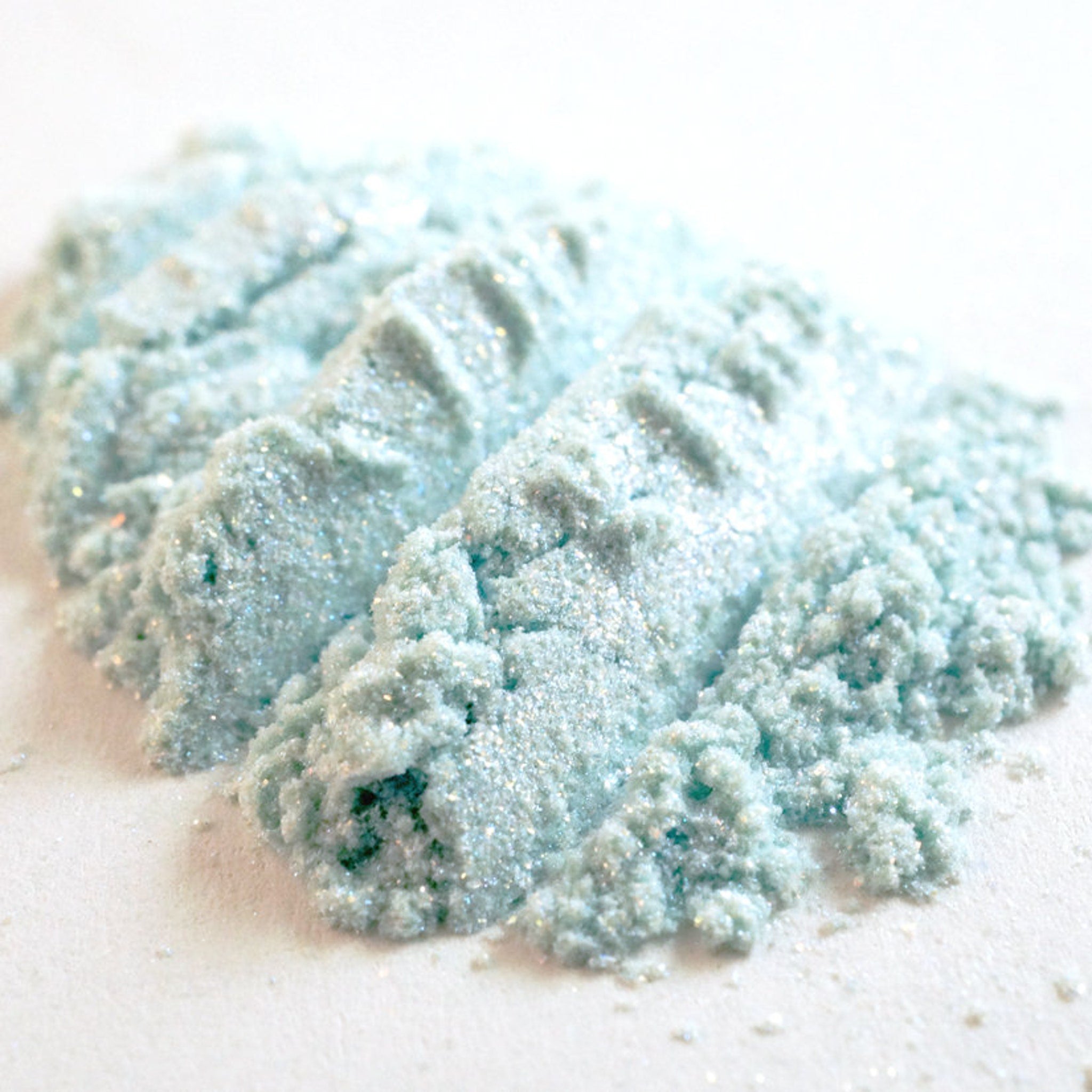 Close-up of turquoise and orange iridescent eye shadow with shimmer particles, showing color shift in light