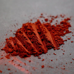Side view of blood red metallic loose mineral eyeshadow in open jar showing rich pigmentation and shimmer