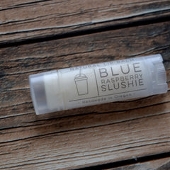 Lip balm tube with clear plastic, white label, and "Blue Raspberry Slushie" text