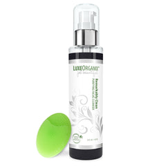 Facial cleanser bottle with silver pump, white label, and green silicone brush next to it