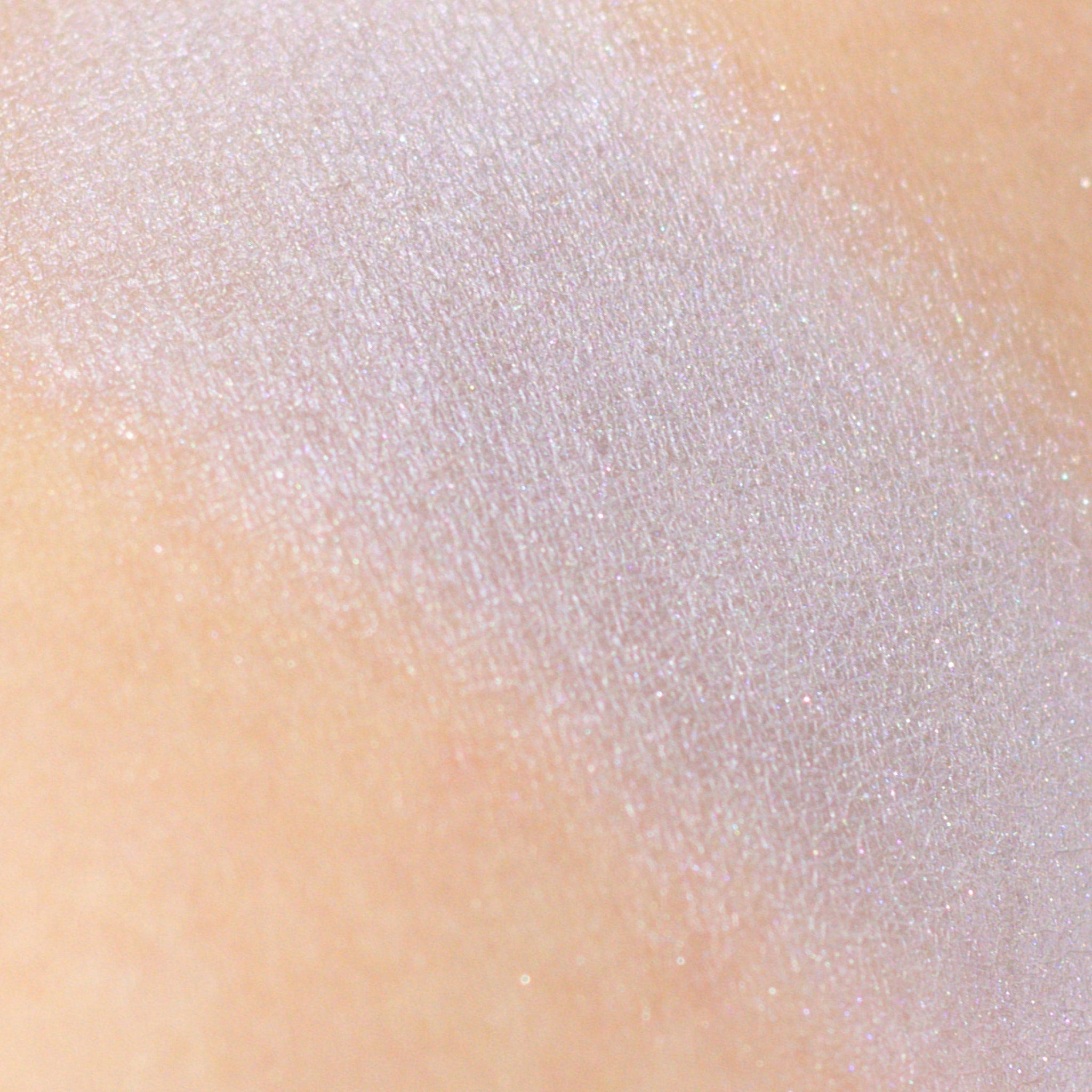 Side angle of frosty silver-gray eyeshadow pan with lavender shimmer, showcasing mineral texture and vegan makeup details