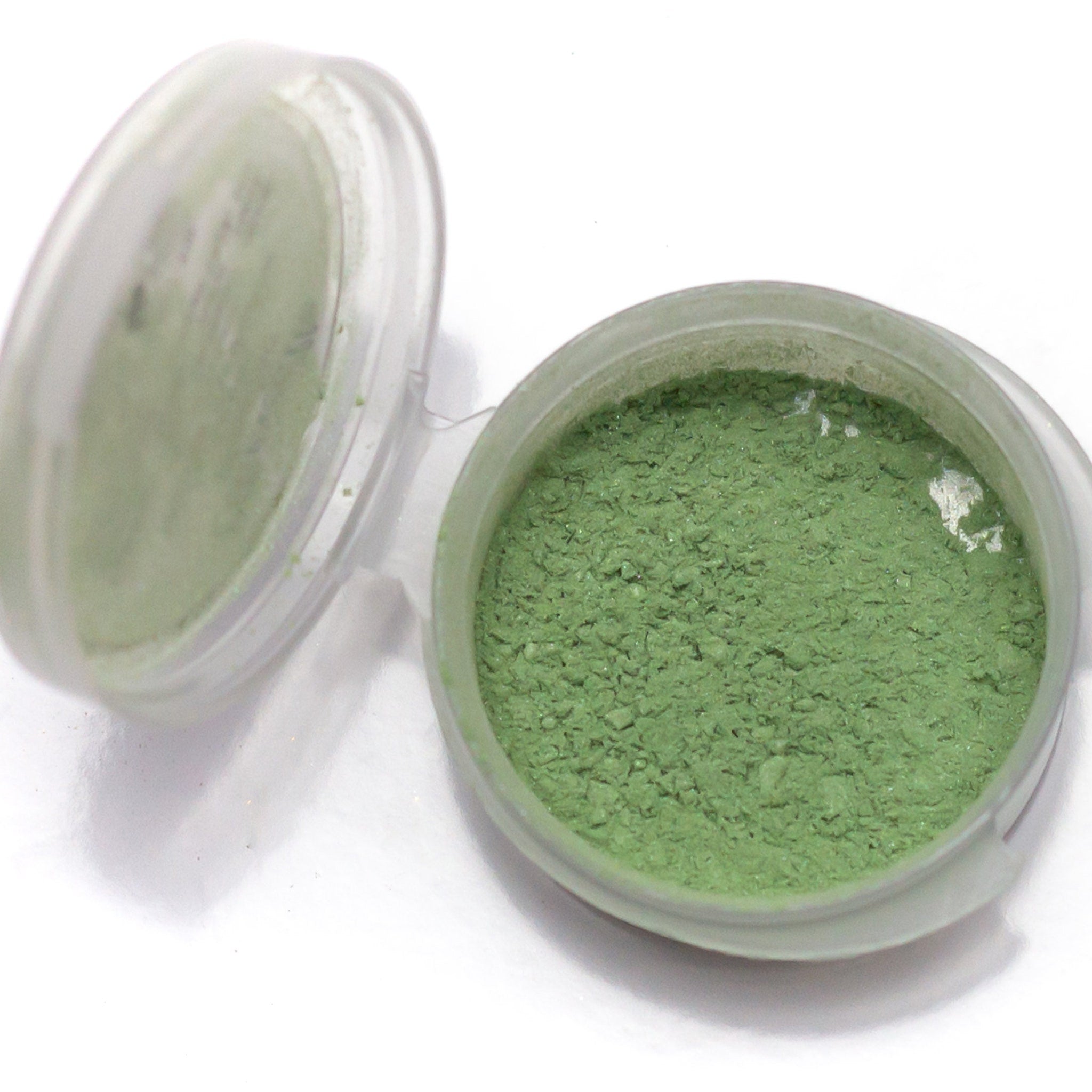 Close-up of shimmery pistachio eyeshadow being applied to eyelid with brush, showcasing light spring green pigment.