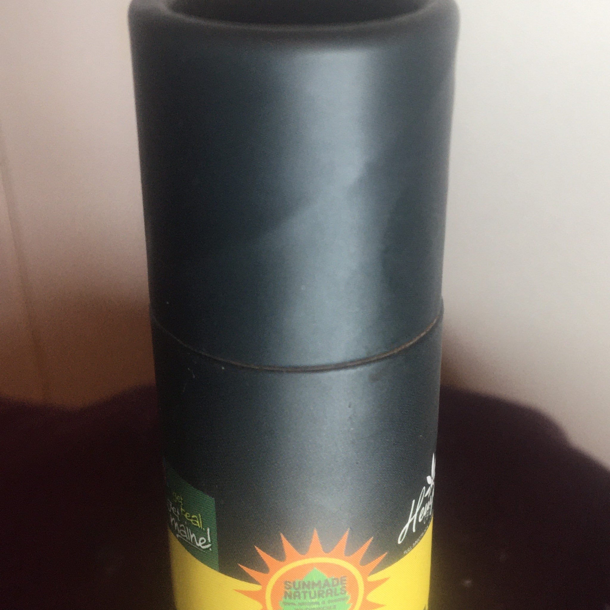 Black cylindrical container with yellow and green accents, Sunmade Naturals branding visible