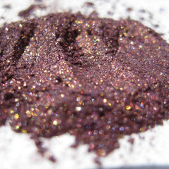 Close-up of smoky plum eyeshadow with iridescent copper shimmer being applied to eyelid with brush