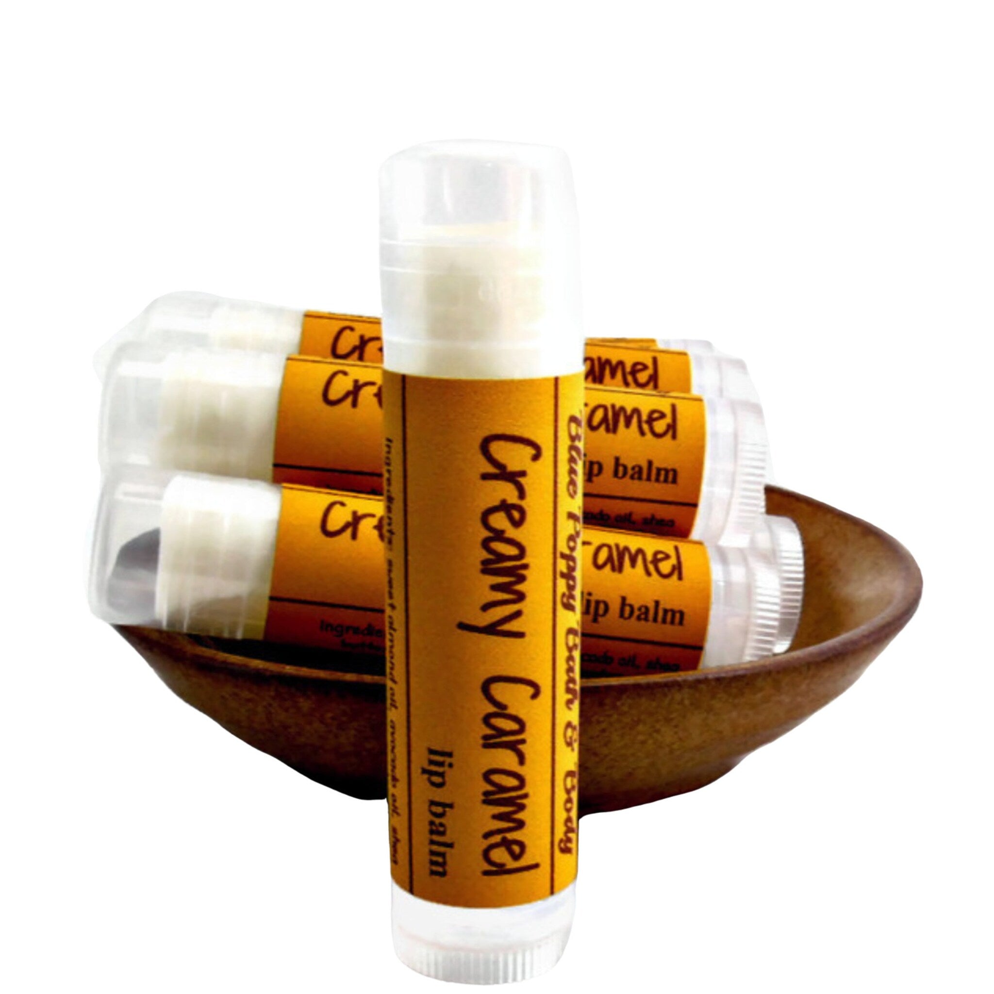 Lip balm tubes with white and brown labels in a wooden bowl, "Creamy Caramel" text visible