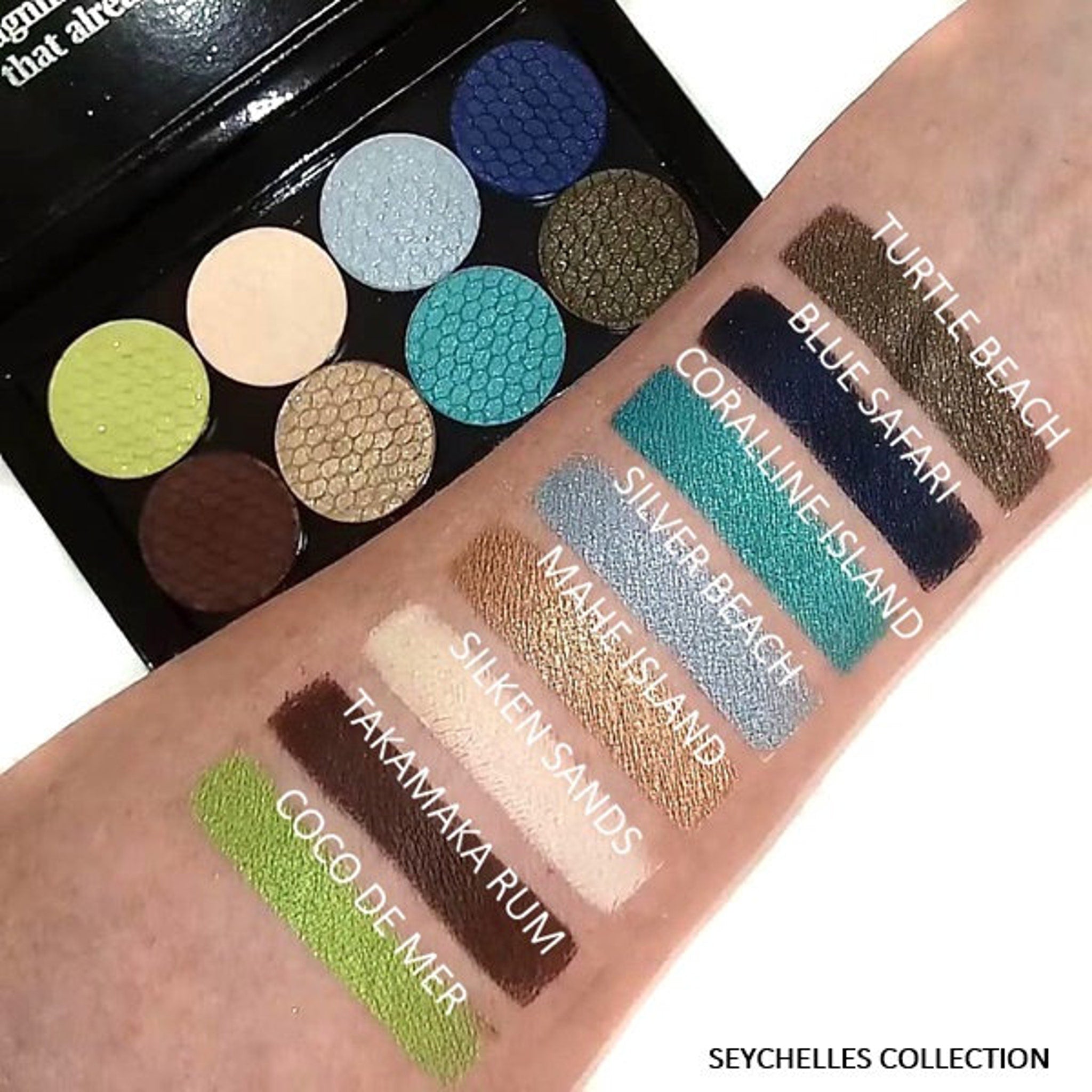 Eyeshadow palette with various colors and textures, swatches on arm, Seychelles Collection text visible