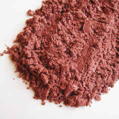 Close-up of passion fruit mineral eye shadow showing vibrant pink hue with shimmer particles in compact case