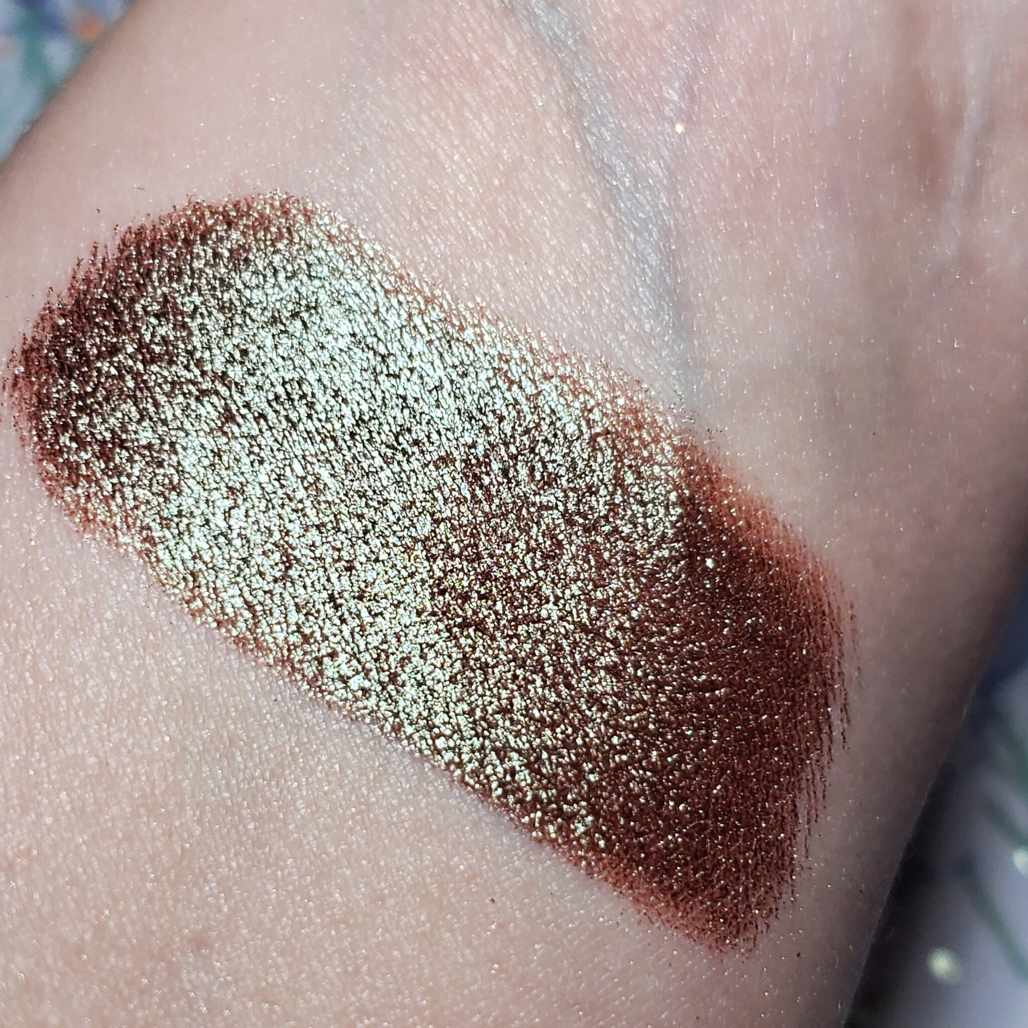 Side view of Kelpie Eye Shadow compact showcasing its sleek black case and shimmering bronze powder