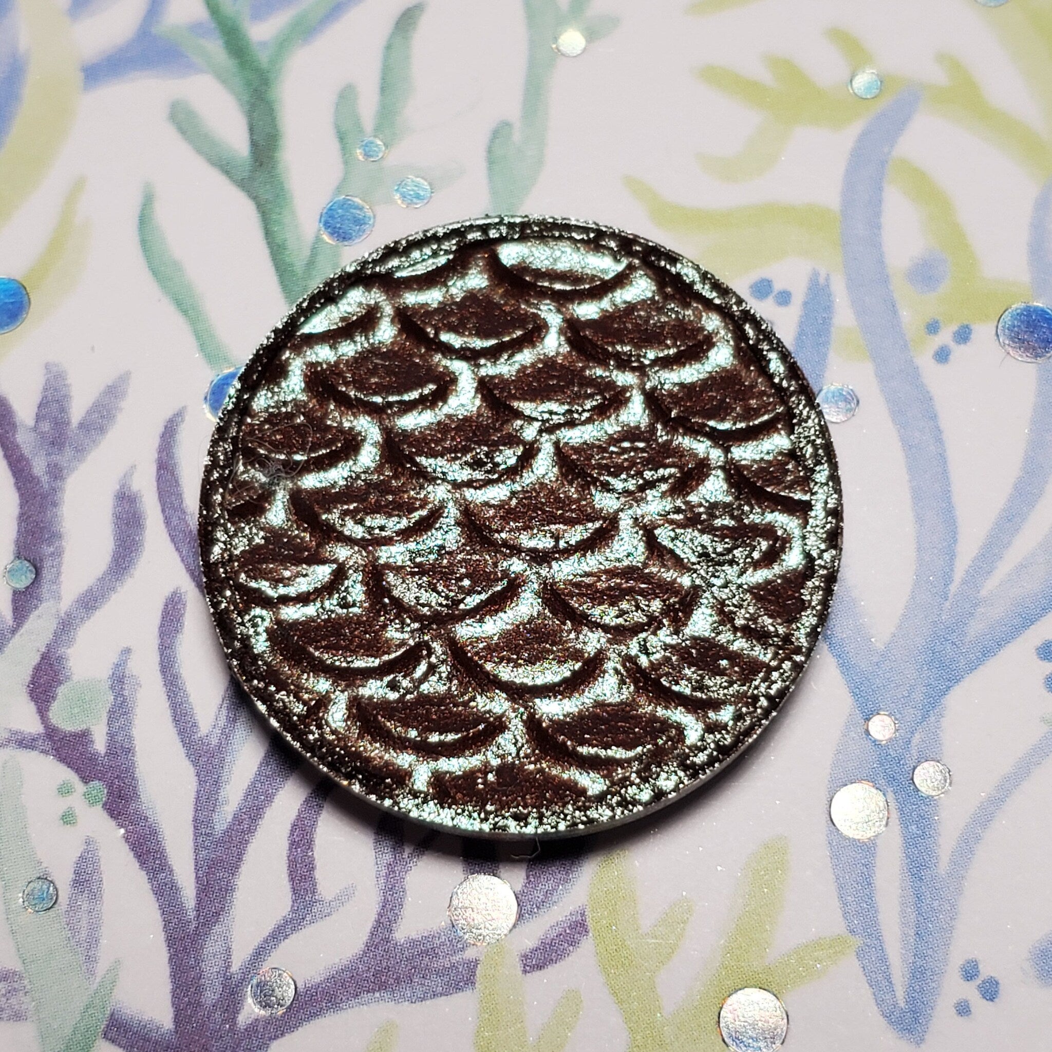 Close-up of Kelpie Eye Shadow pan showing shimmering taupe pigment with smooth satin finish