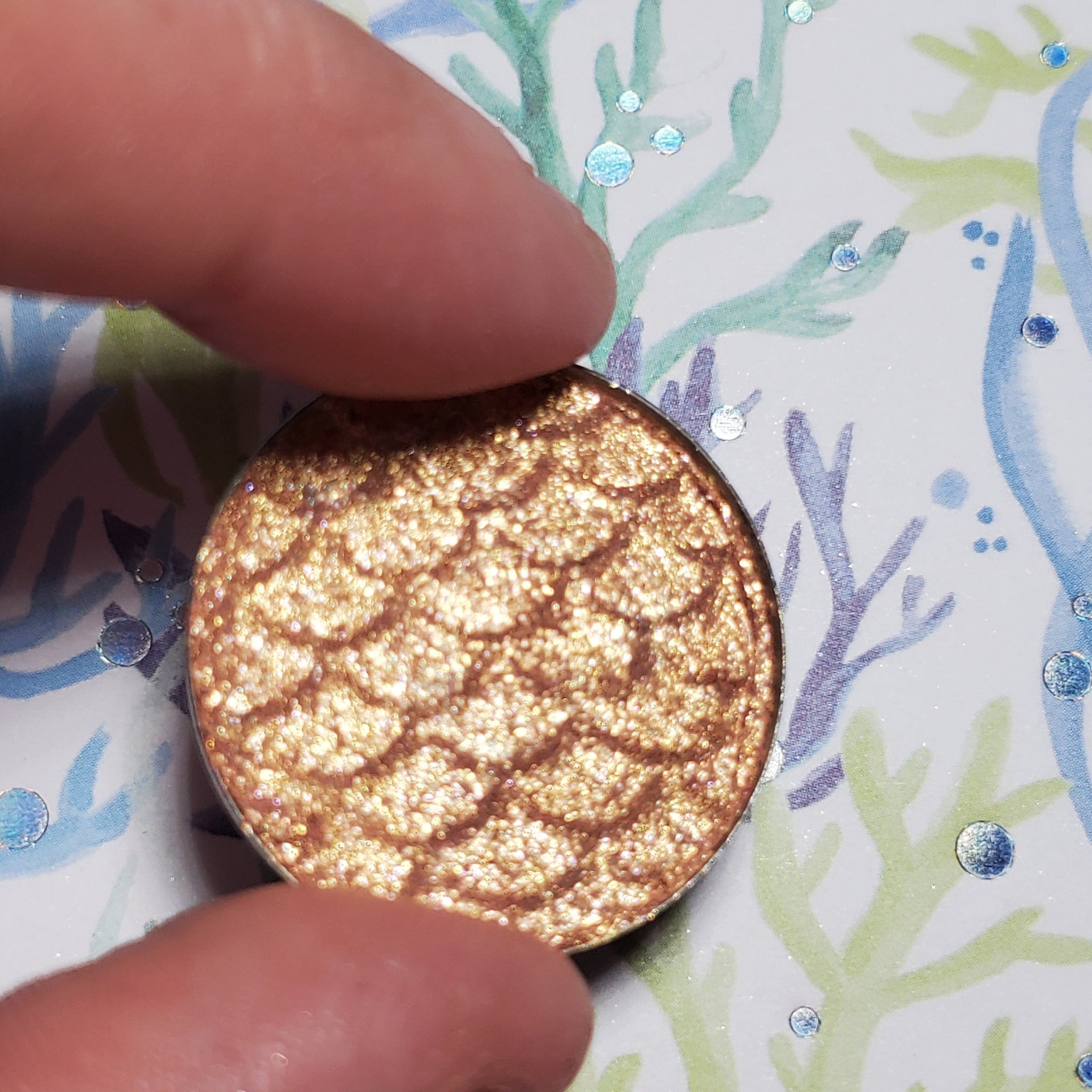 Side view of Dobby Eye Shadow compact showcasing its sleek black case and shimmering bronze powder.