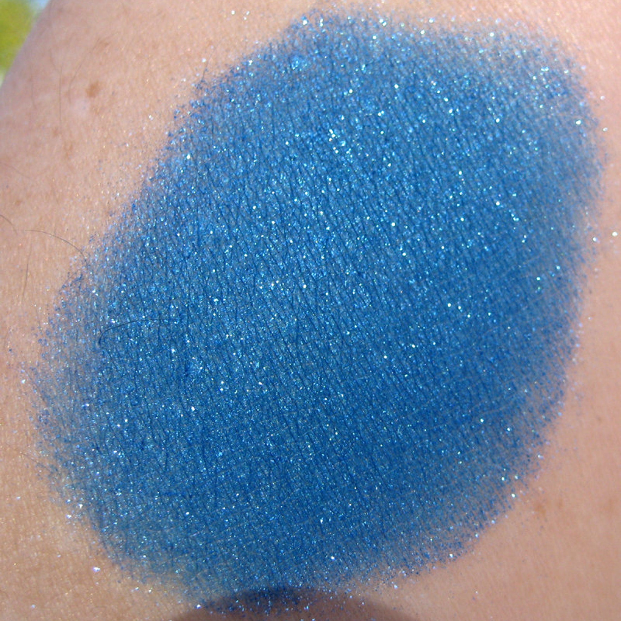 Side view of iridescent royal blue loose mineral eyeshadow with turquoise shimmer in a clear jar